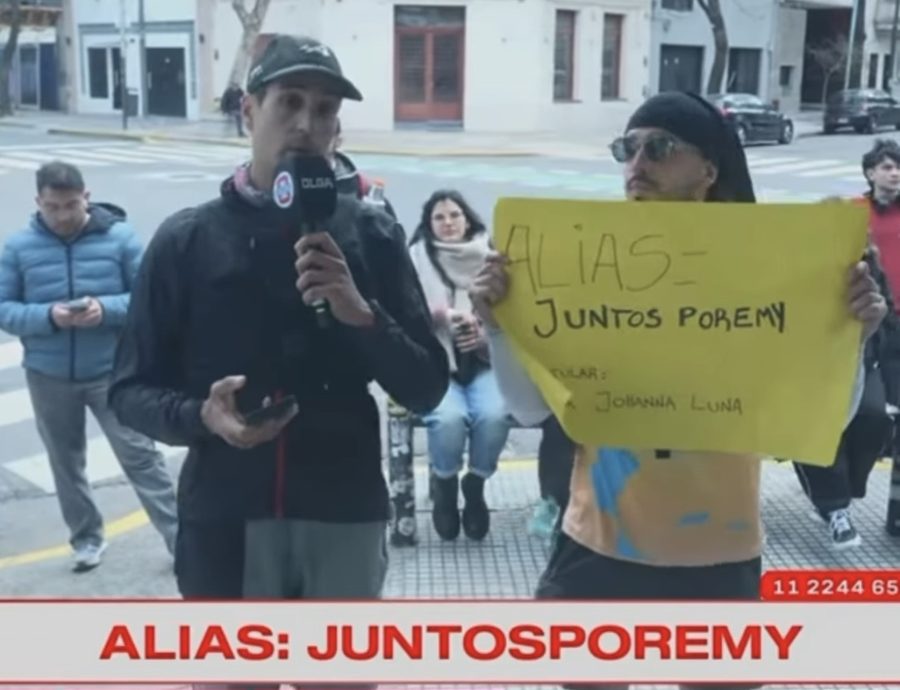 Gastón Gennai entrevistado en vivo en la calle, frente al estudio de Olga, junto a un cartel con el alias JUNTOSPOREMY; en pantalla se lee ALIAS: JUNTOSPOREMY